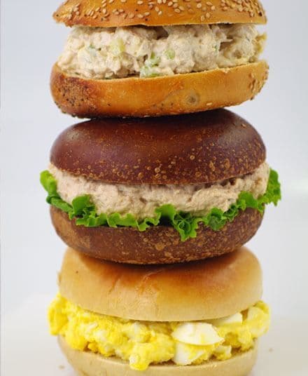 Stack of breakfast bagel sandwiches with egg, tuna and chicken salad